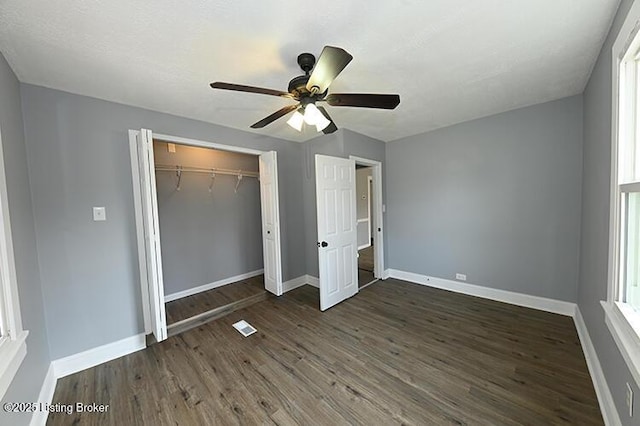 unfurnished bedroom featuring dark wood-style floors, baseboards, and a closet