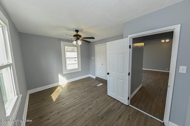 unfurnished bedroom with a ceiling fan, dark wood-style floors, baseboards, and a closet