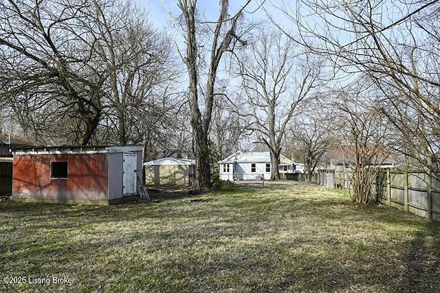 view of yard featuring a storage shed, an outdoor structure, and fence