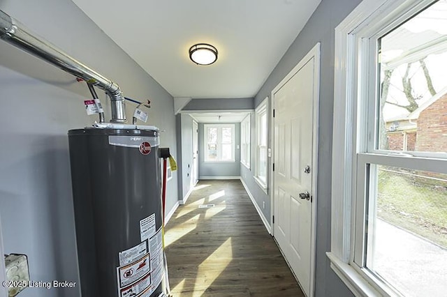 hall with water heater, dark wood finished floors, and baseboards