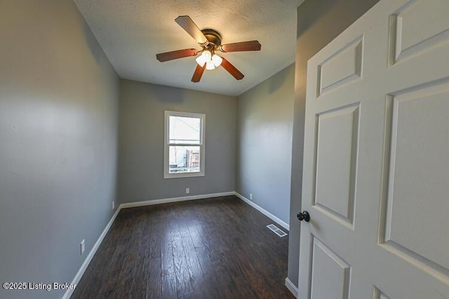 empty room with wood finished floors, baseboards, visible vents, and a textured ceiling