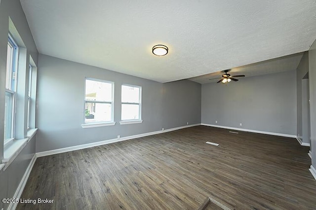 empty room with baseboards, dark wood-type flooring, and a textured ceiling