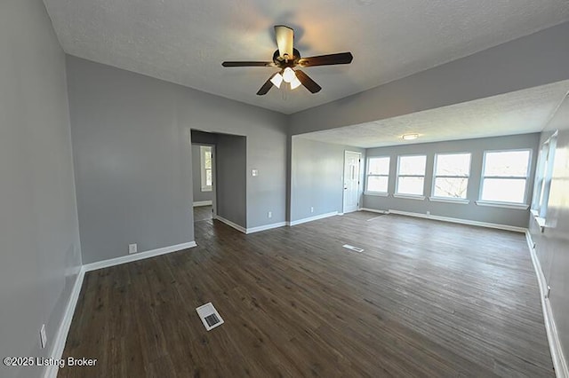 empty room featuring visible vents, baseboards, a textured ceiling, and dark wood finished floors