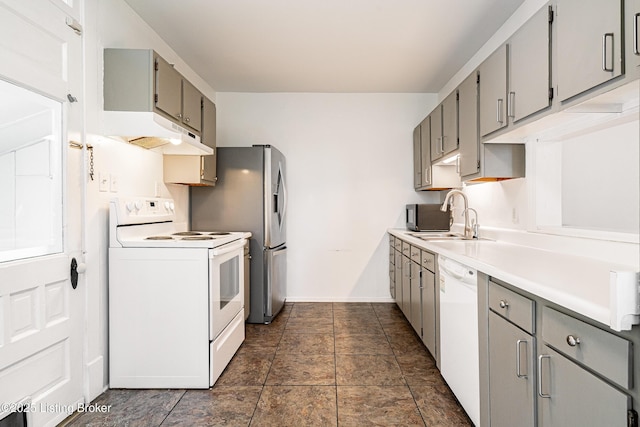 kitchen with gray cabinets, a sink, white appliances, light countertops, and baseboards