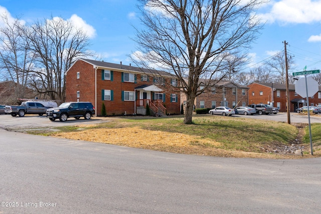 view of front facade featuring a front lawn, brick siding, and a residential view