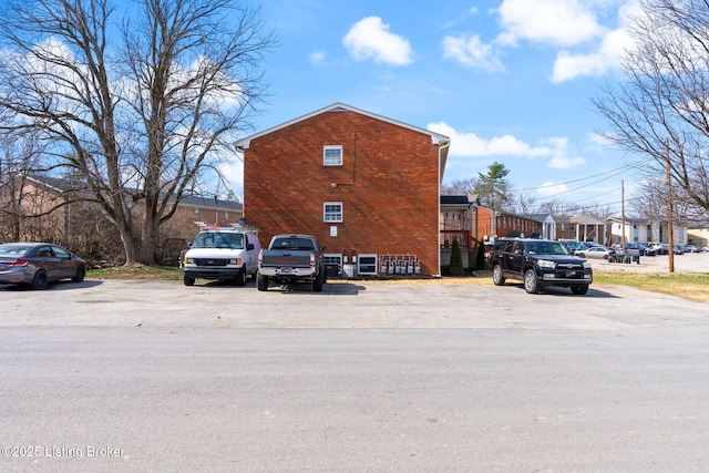 exterior space with uncovered parking and brick siding