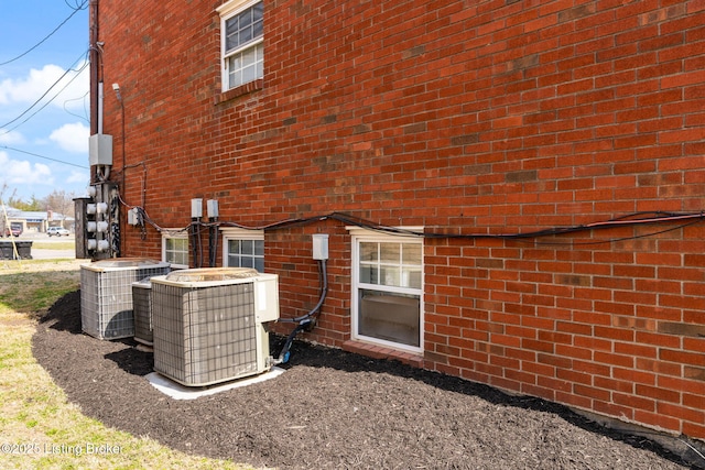 back of property featuring brick siding and central AC unit