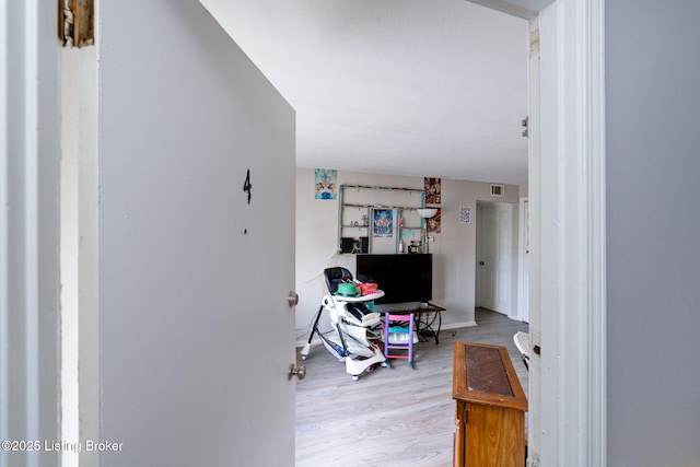 hallway with visible vents, baseboards, and wood finished floors