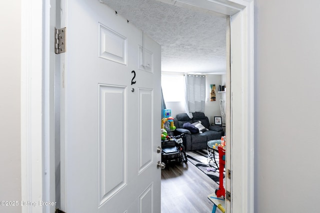 corridor featuring light wood-type flooring and a textured ceiling