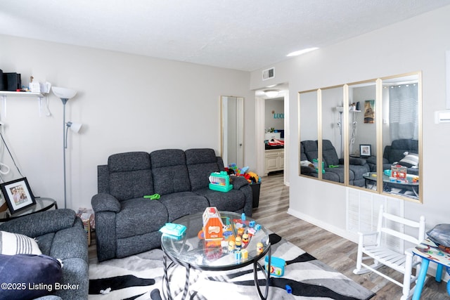 living area with wood finished floors, visible vents, and a textured ceiling