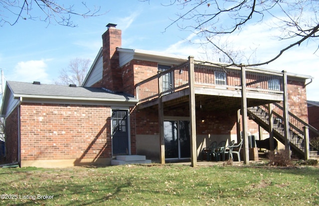 rear view of property with stairway, a yard, a chimney, a deck, and brick siding