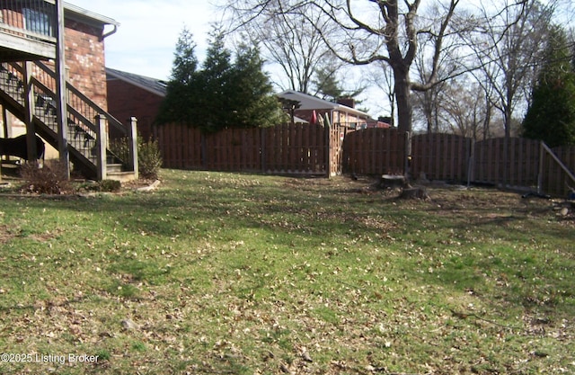 view of yard with fence, stairs, and a gate