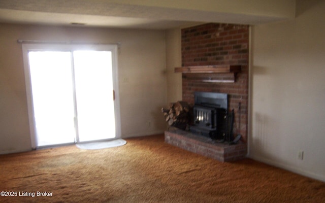 unfurnished living room with carpet, a healthy amount of sunlight, and a wood stove