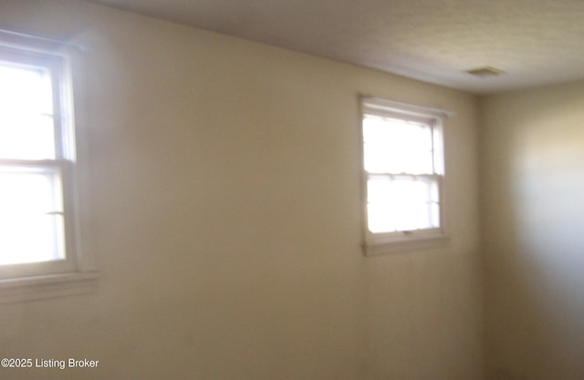 empty room featuring a wealth of natural light and visible vents