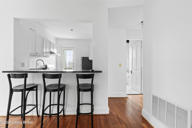 kitchen featuring dark countertops, white cabinets, visible vents, and dark wood-type flooring