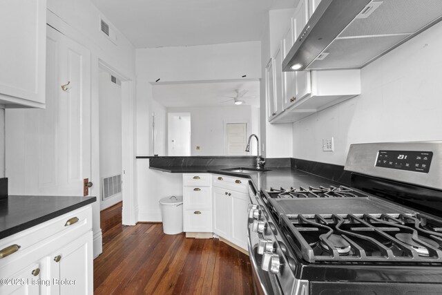 kitchen featuring dark countertops, a sink, extractor fan, stainless steel gas range, and dark wood-style flooring