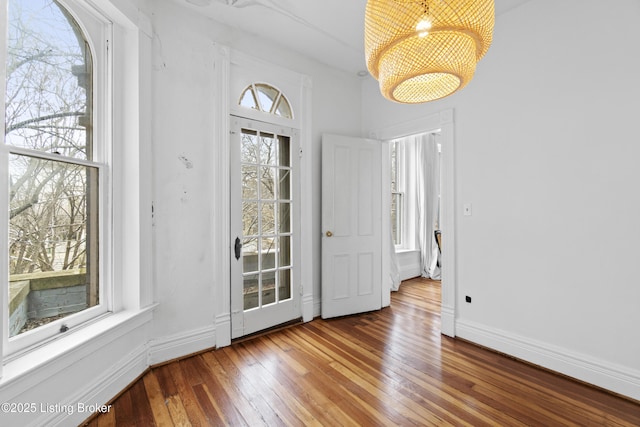 entryway featuring baseboards, wood-type flooring, and a chandelier