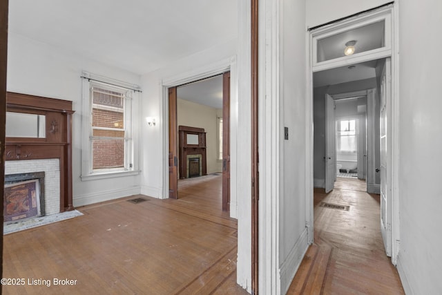 corridor featuring visible vents, wood-type flooring, and baseboards