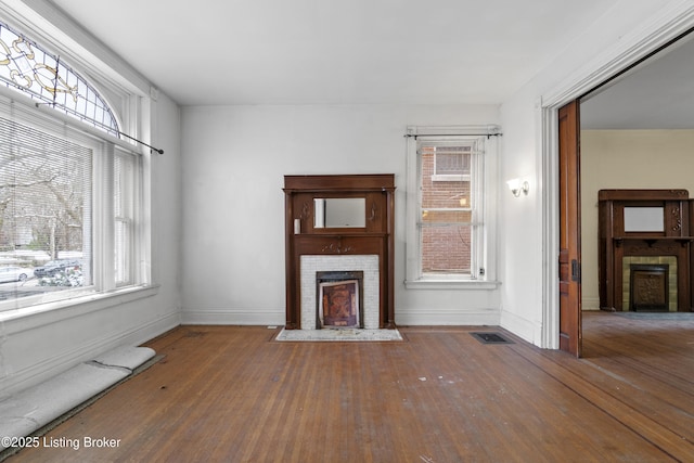 unfurnished living room with baseboards, a brick fireplace, and hardwood / wood-style floors