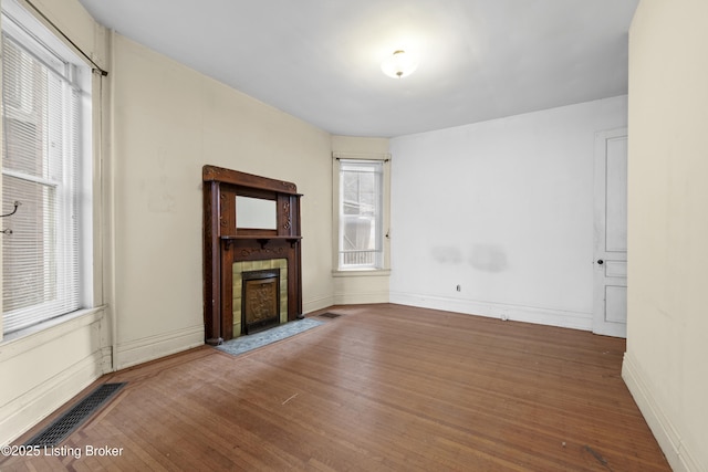 unfurnished living room with visible vents, baseboards, wood finished floors, and a fireplace