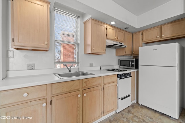 kitchen with under cabinet range hood, light brown cabinetry, light countertops, white appliances, and a sink