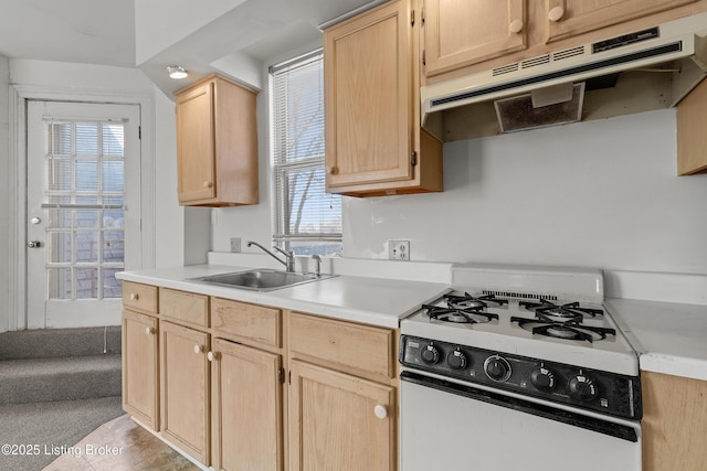 kitchen with light brown cabinetry, under cabinet range hood, a sink, range with gas cooktop, and light countertops