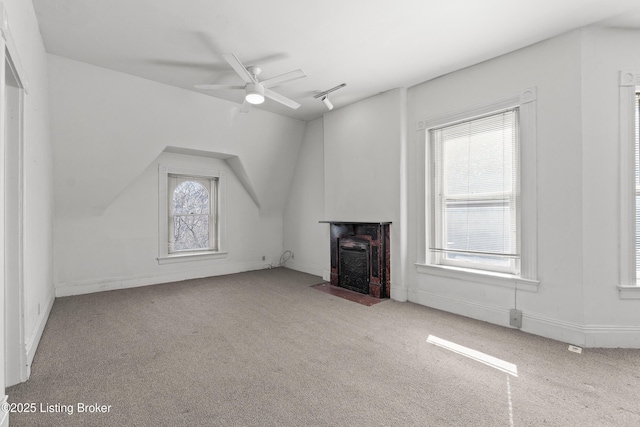 unfurnished living room with a wealth of natural light, a ceiling fan, carpet, and vaulted ceiling