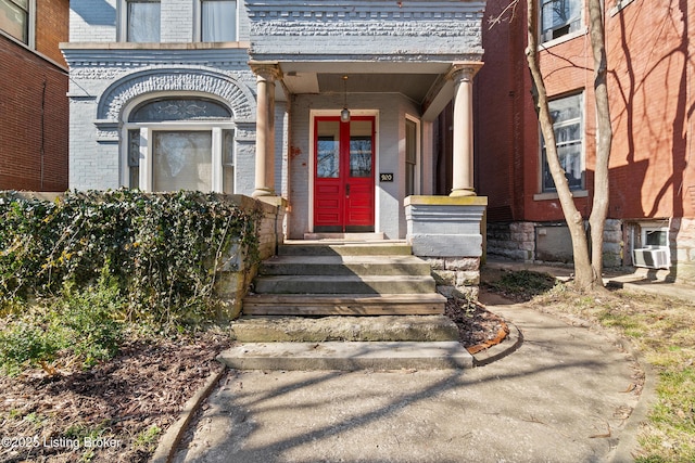 property entrance featuring cooling unit and brick siding