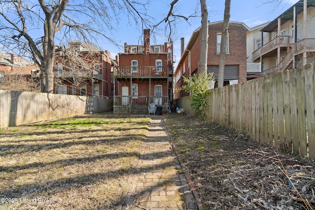 rear view of property featuring brick siding, a fenced backyard, and a garage