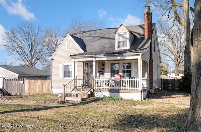 cape cod house with covered porch, a chimney, a front yard, and fence