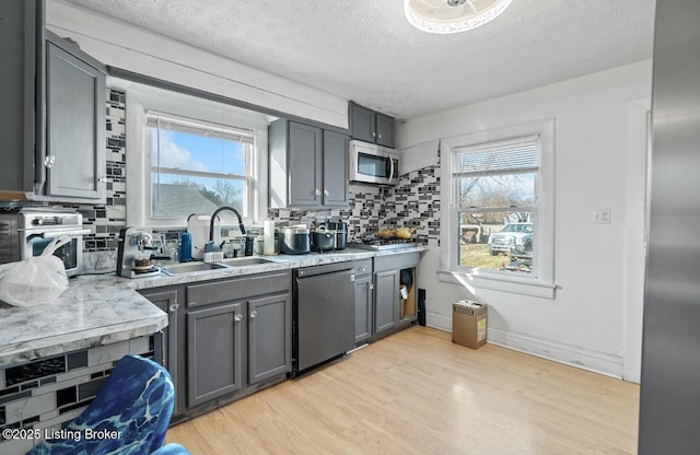 kitchen featuring stainless steel microwave, gray cabinetry, dishwashing machine, and a healthy amount of sunlight