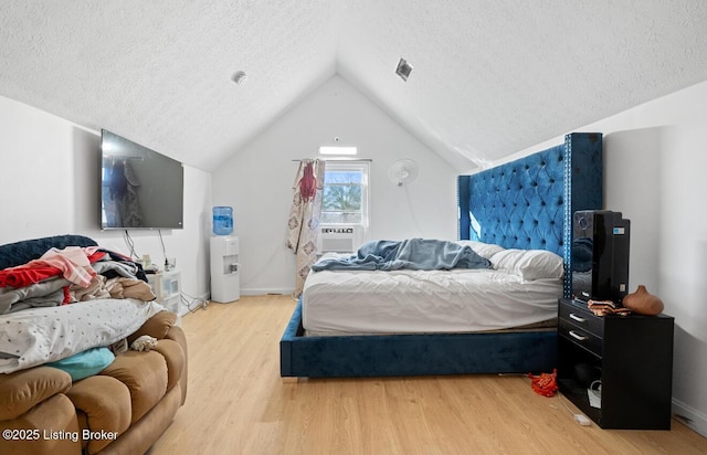 bedroom with a textured ceiling, wood finished floors, cooling unit, baseboards, and vaulted ceiling