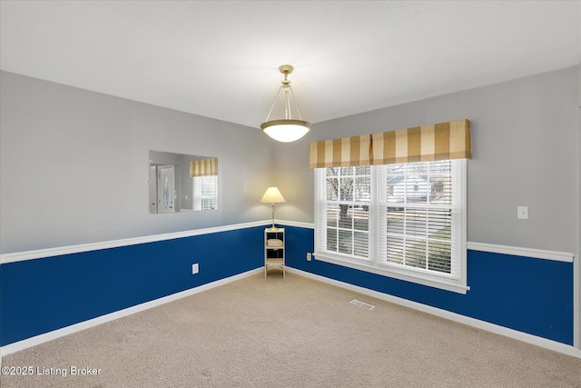 carpeted spare room featuring visible vents and baseboards