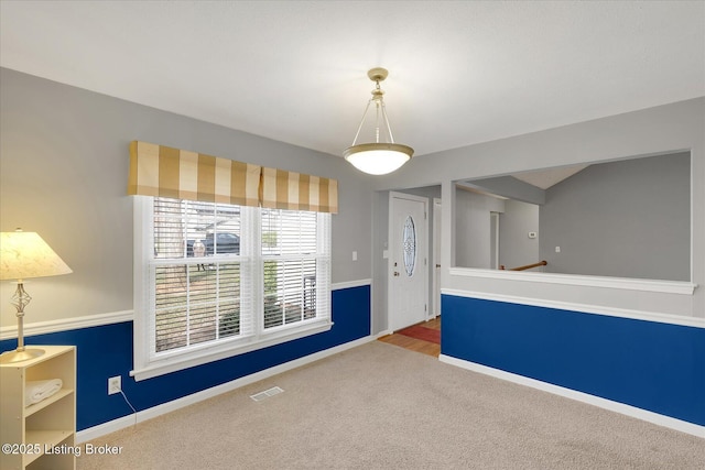 carpeted spare room with visible vents and baseboards