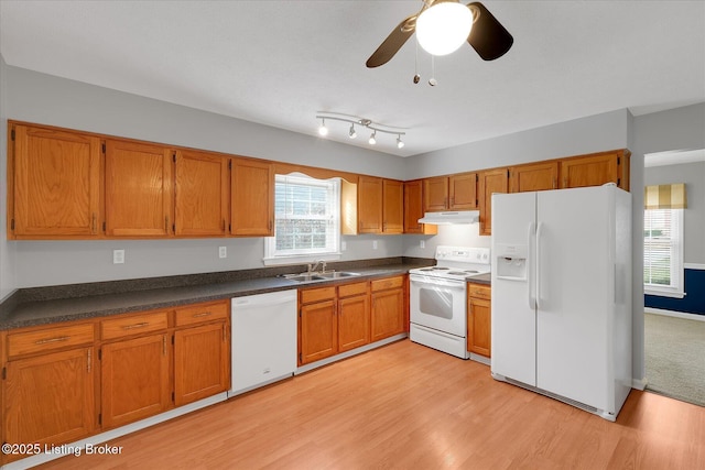 kitchen with under cabinet range hood, white appliances, dark countertops, and a sink