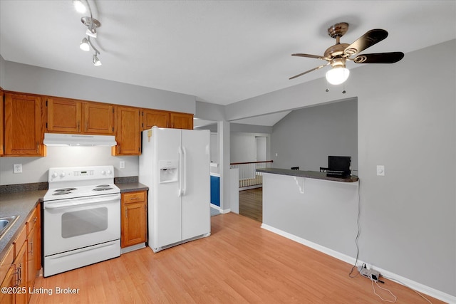 kitchen featuring dark countertops, under cabinet range hood, brown cabinets, light wood-style floors, and white appliances