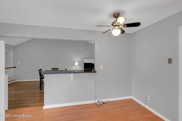 kitchen featuring dark countertops, baseboards, light wood finished floors, and ceiling fan