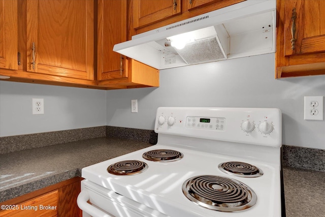 kitchen featuring under cabinet range hood, dark countertops, brown cabinetry, and electric stove