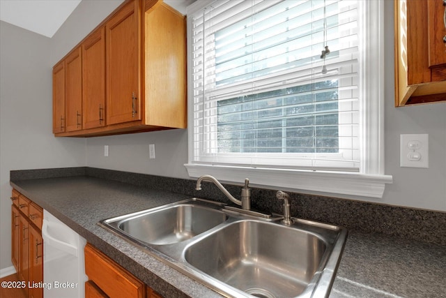 kitchen with a sink, plenty of natural light, dark countertops, and brown cabinetry