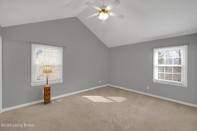 carpeted spare room featuring lofted ceiling, visible vents, baseboards, and ceiling fan