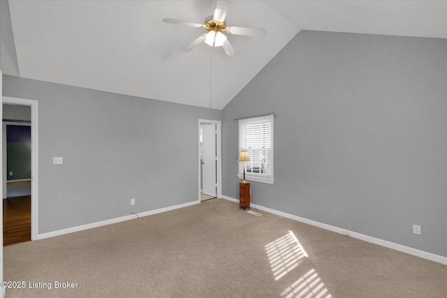 carpeted spare room with high vaulted ceiling, baseboards, and a ceiling fan