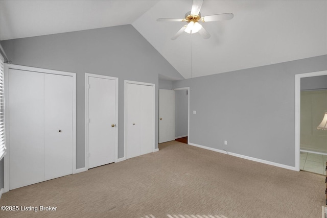 unfurnished bedroom featuring baseboards, high vaulted ceiling, multiple closets, carpet flooring, and connected bathroom