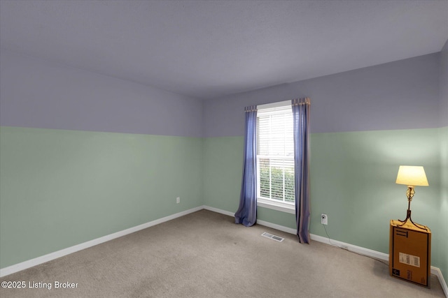 spare room featuring carpet flooring, baseboards, visible vents, and vaulted ceiling