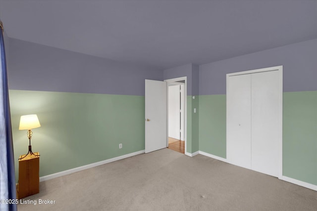 unfurnished bedroom with a closet, carpet floors, lofted ceiling, and baseboards