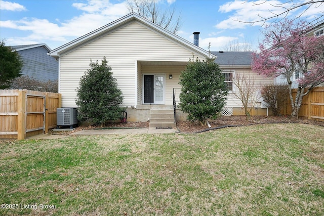 back of property with central air condition unit, a yard, and fence