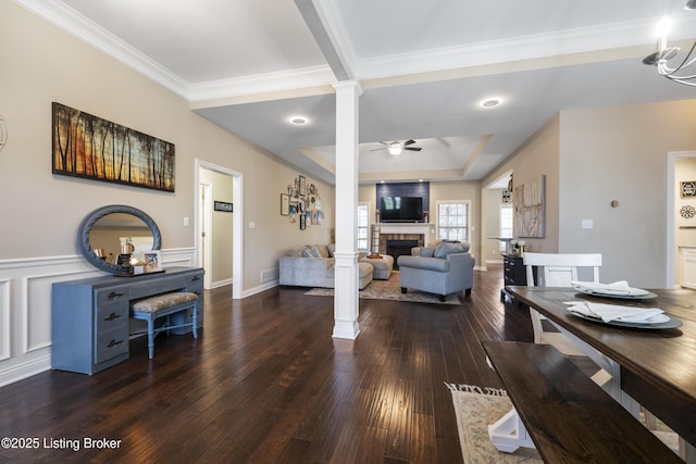 living room featuring hardwood / wood-style floors, ornate columns, a fireplace, a decorative wall, and a ceiling fan