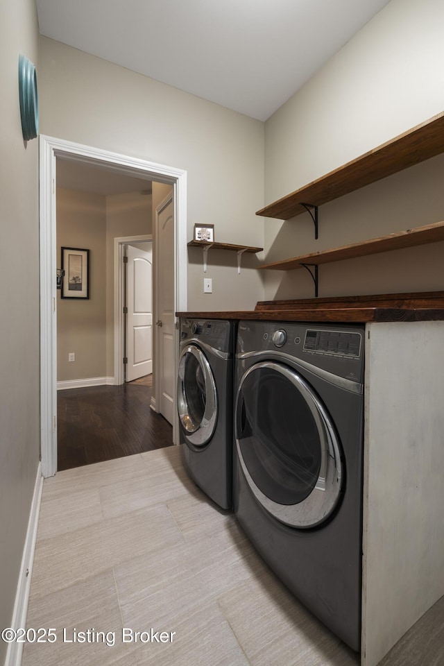 laundry room featuring laundry area, wood finished floors, baseboards, and separate washer and dryer