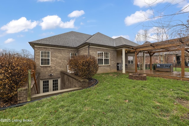 back of property with brick siding, a shingled roof, an outdoor fire pit, a lawn, and a pergola