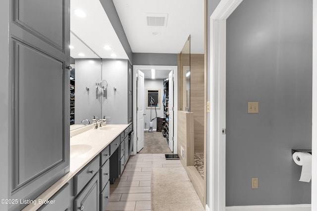 bathroom featuring double vanity, visible vents, a walk in closet, and a sink