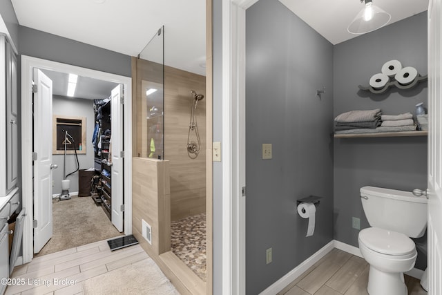 bathroom with toilet, a walk in shower, baseboards, and wood finish floors